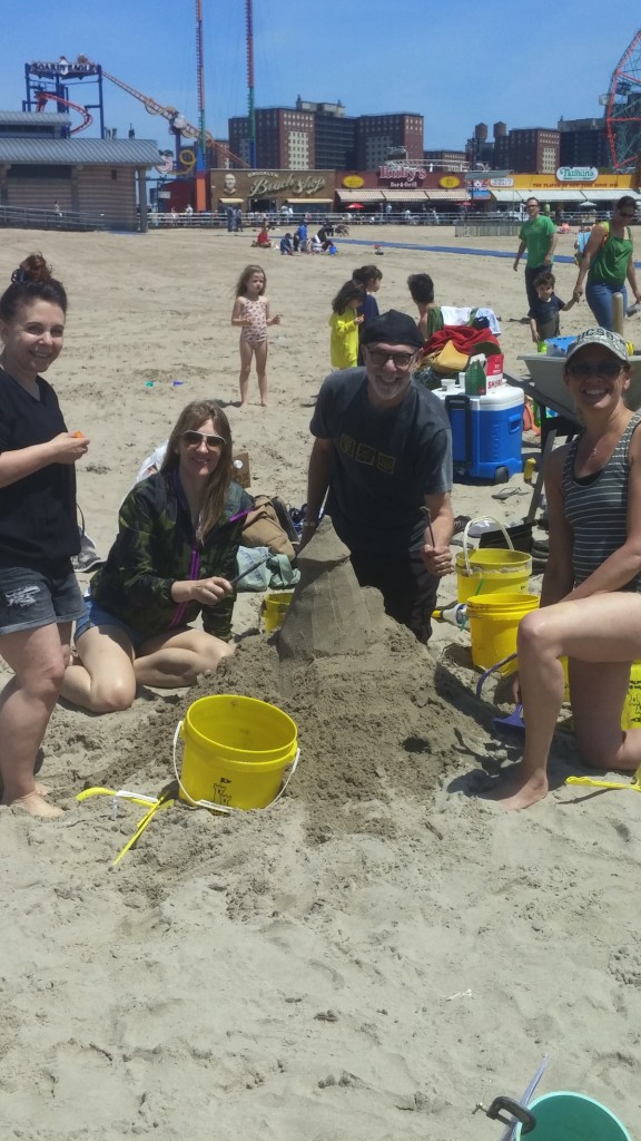 team of 4 around their tall sand castle